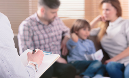 Doctor with a clipboard having a discussion with two parents and their male child.