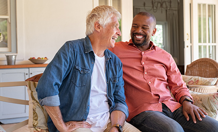 Two men sitting on patio furniture laughing