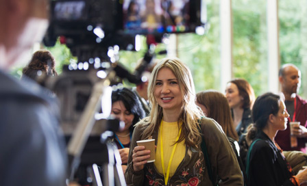 Cameraman videoing woman drinking coffee at conference