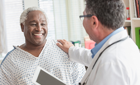 Doctor with digital tablet comforting older man in hospital