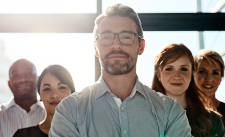 Cropped shot of a businessman posing with his arms crossed with his colleagues in the background