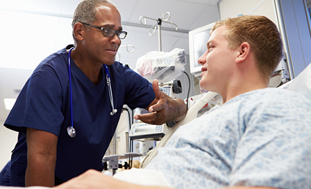 Doctor leaning over bed examining young male patient