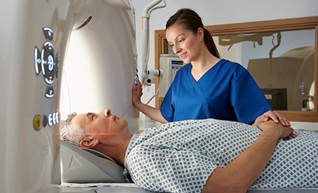 Radiographer reassuring man going into CT scanner