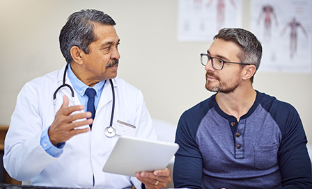 Shot of a confident mature male doctor seated at his desk while consulting a patient inside a hospital during the day