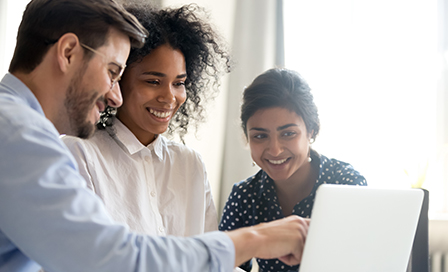 Three people looking over a laptop