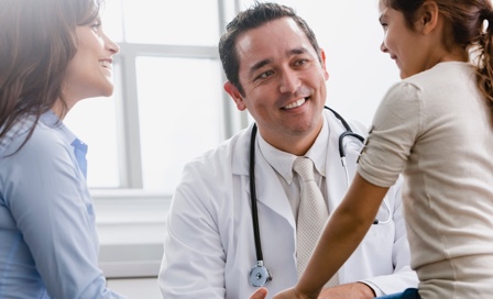 Doctor talking to girl and her mother in examination room