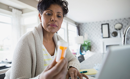 Woman looking at the description on her prescription medicine bottle.